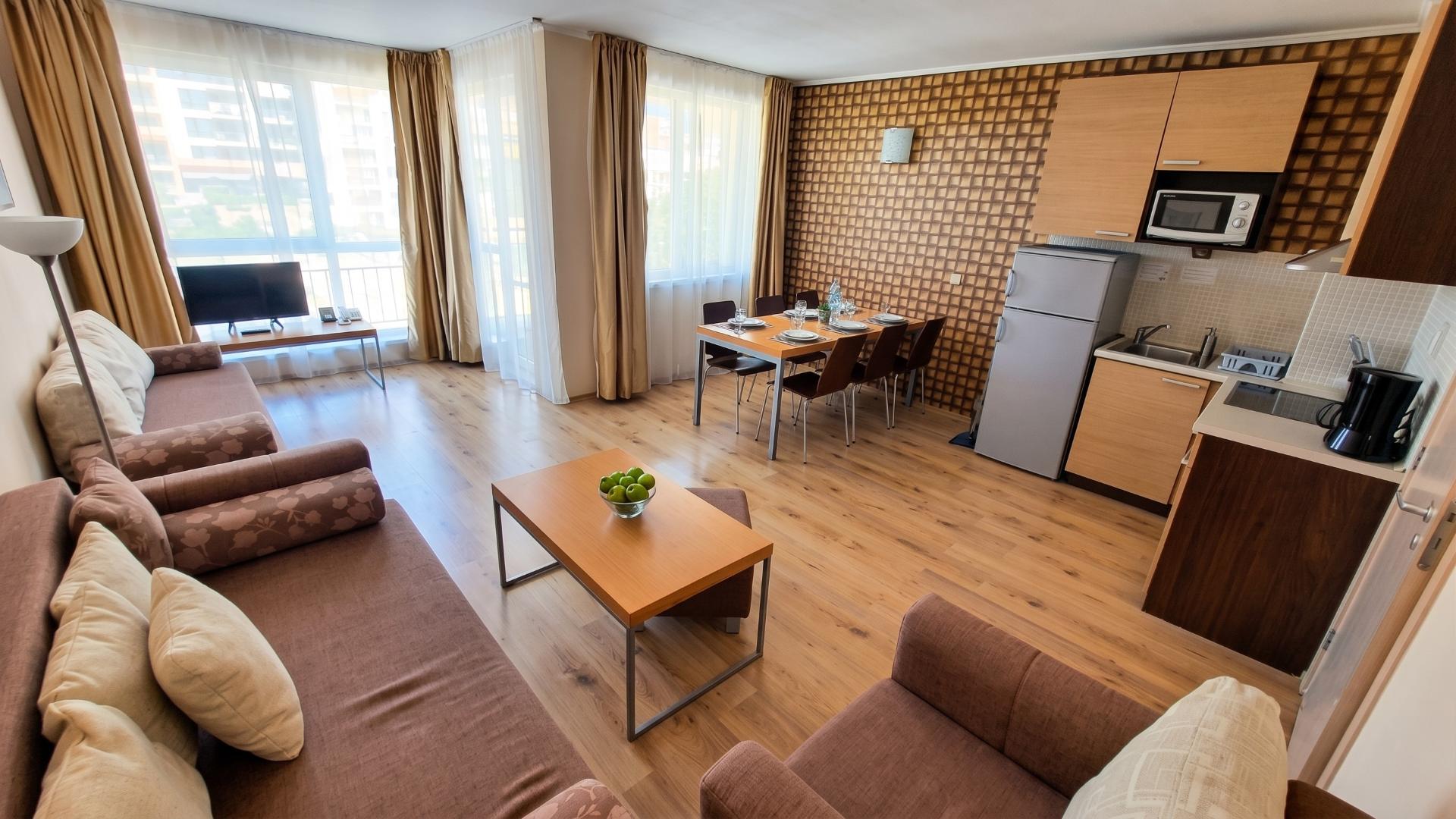 Living room with dining table, kitchen, sofas.